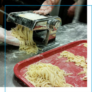 Two hands machine cutting fresh egg pasta